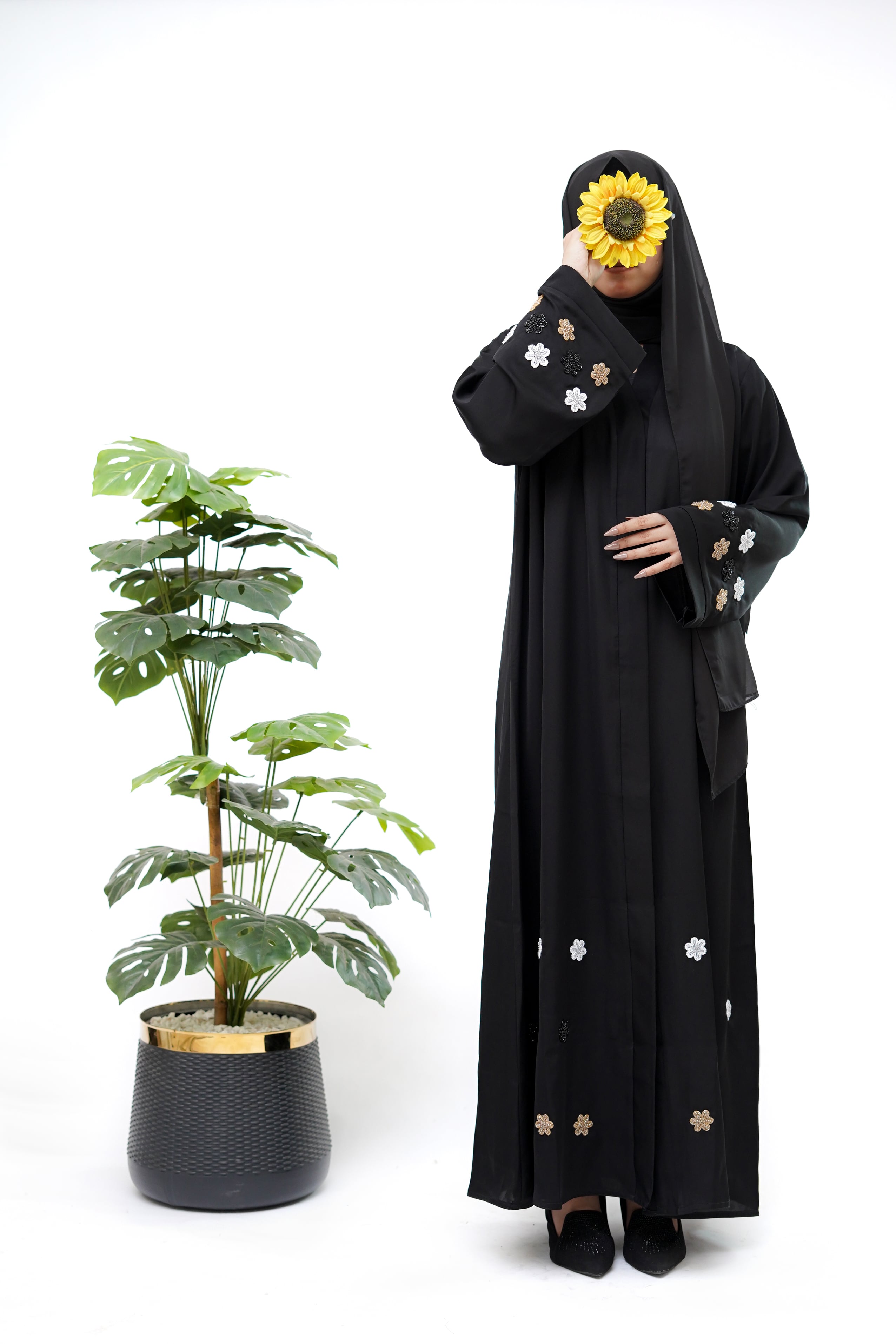 Clarity Glam best black abaya with floral embroidery on sleeves and hem worn by model holding sunflower