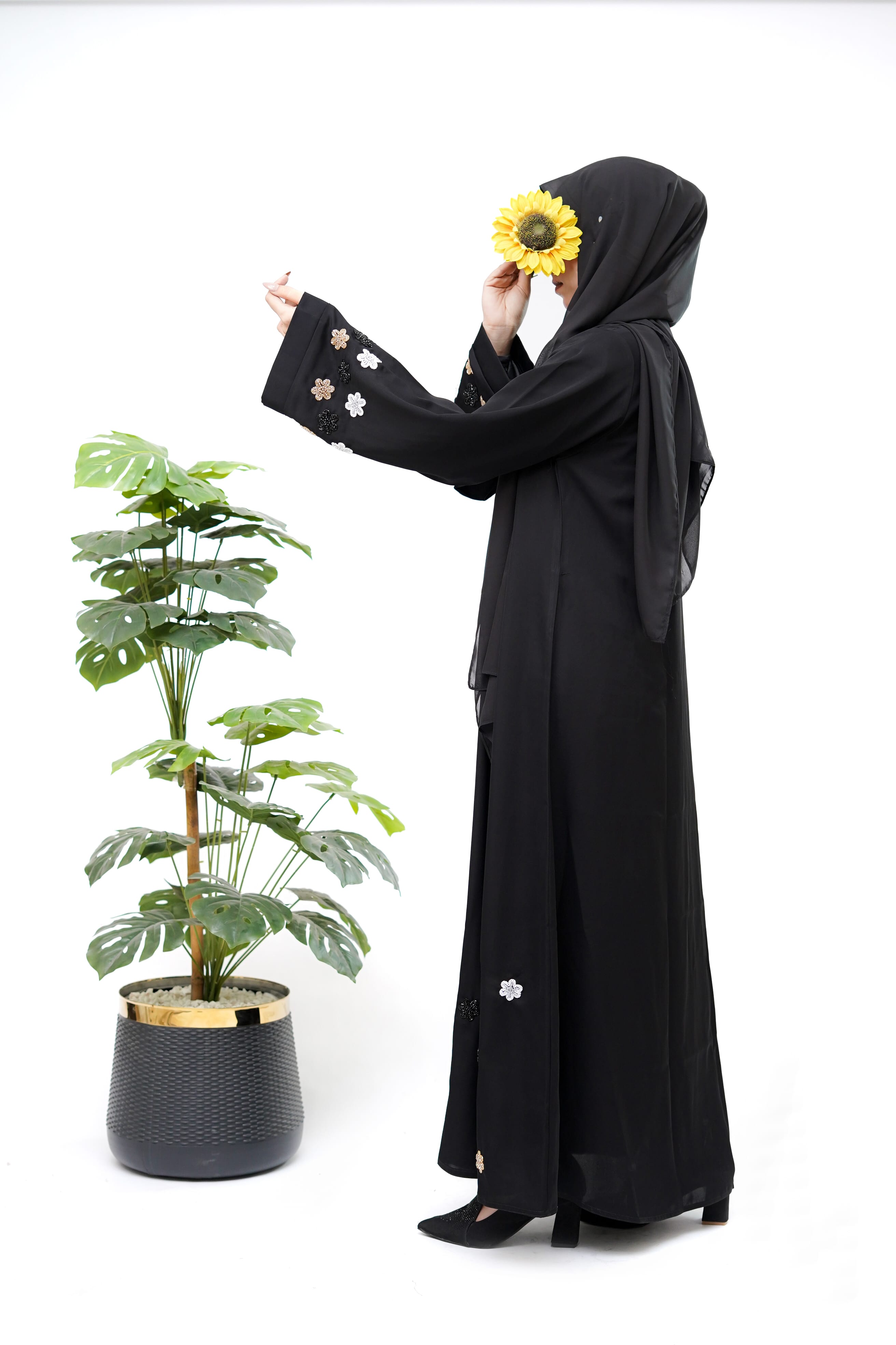 Clarity Glam best black abaya with floral embroidery on sleeves and hem worn by woman holding sunflower