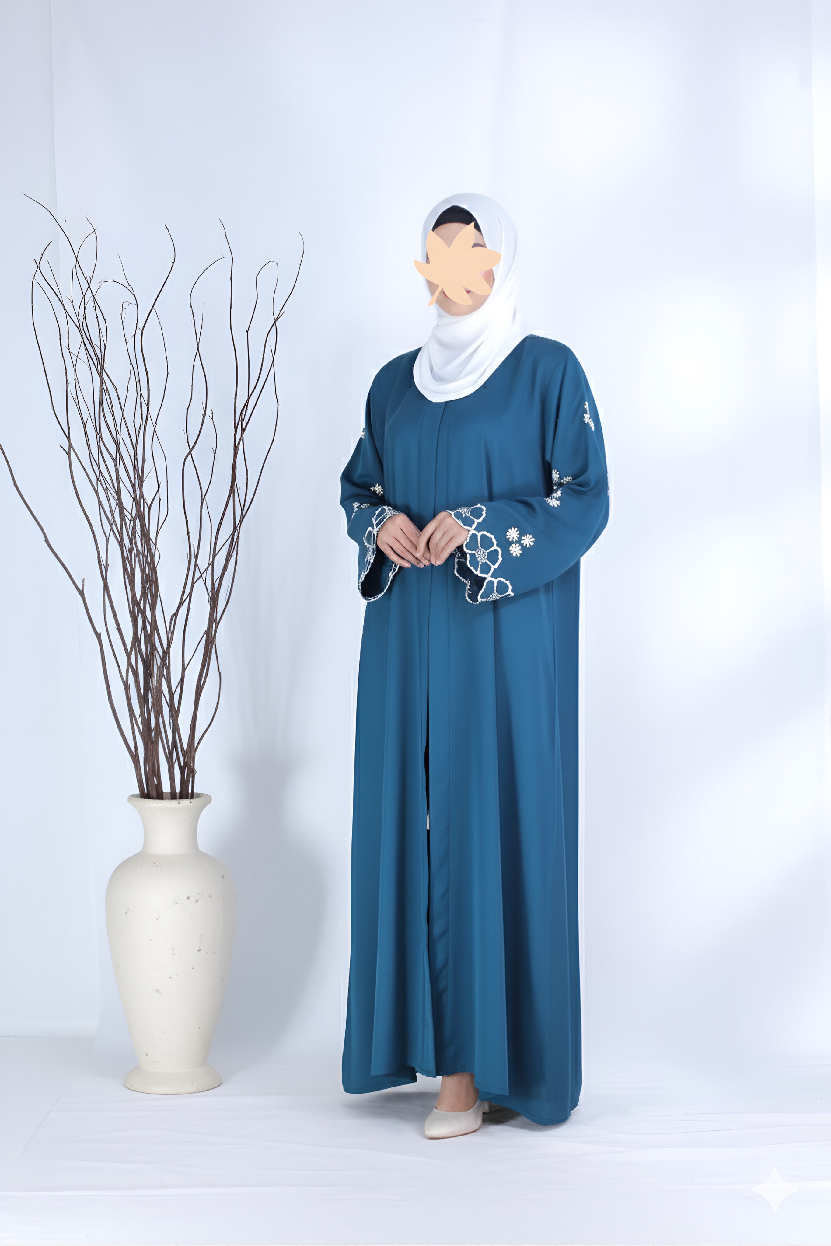 Clarity Glam blue abaya with floral sleeve embroidery worn with a white hijab in a studio