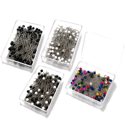 Four boxes of short hijab pins in black, white, black-and-white and multicolour on a white background