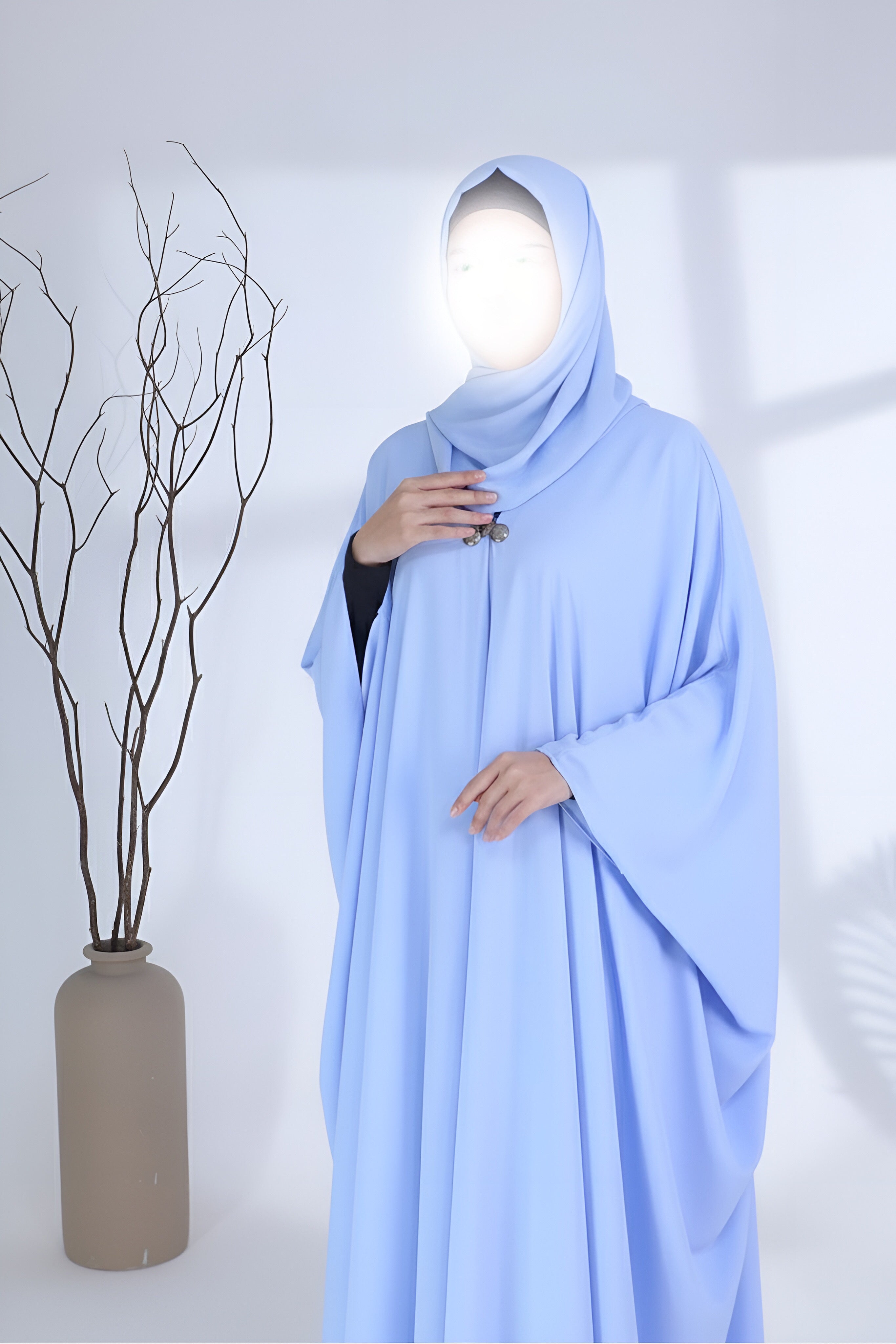Woman wearing a sky blue abaya by Clarity Glam with loose, flowing fabric and matching hijab